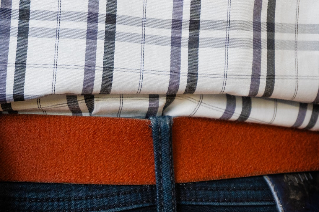 Person wearing a plaid shirt and orange belt.