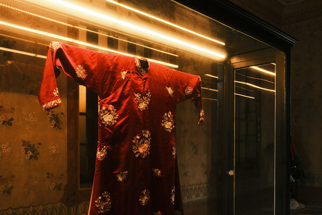 A red ornate robe hangs illuminated by bright lights