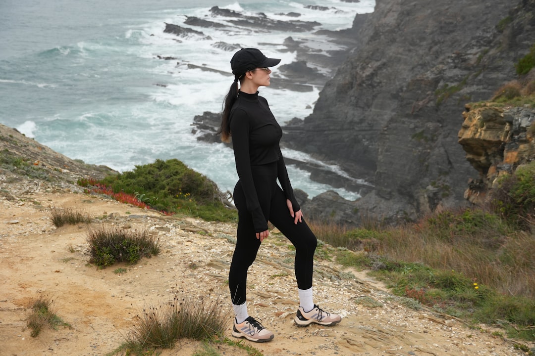 A woman standing on a cliff overlooking the ocean